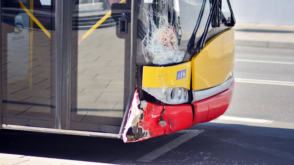 City bus with front-end damage and shattered windshield after a traffic accident