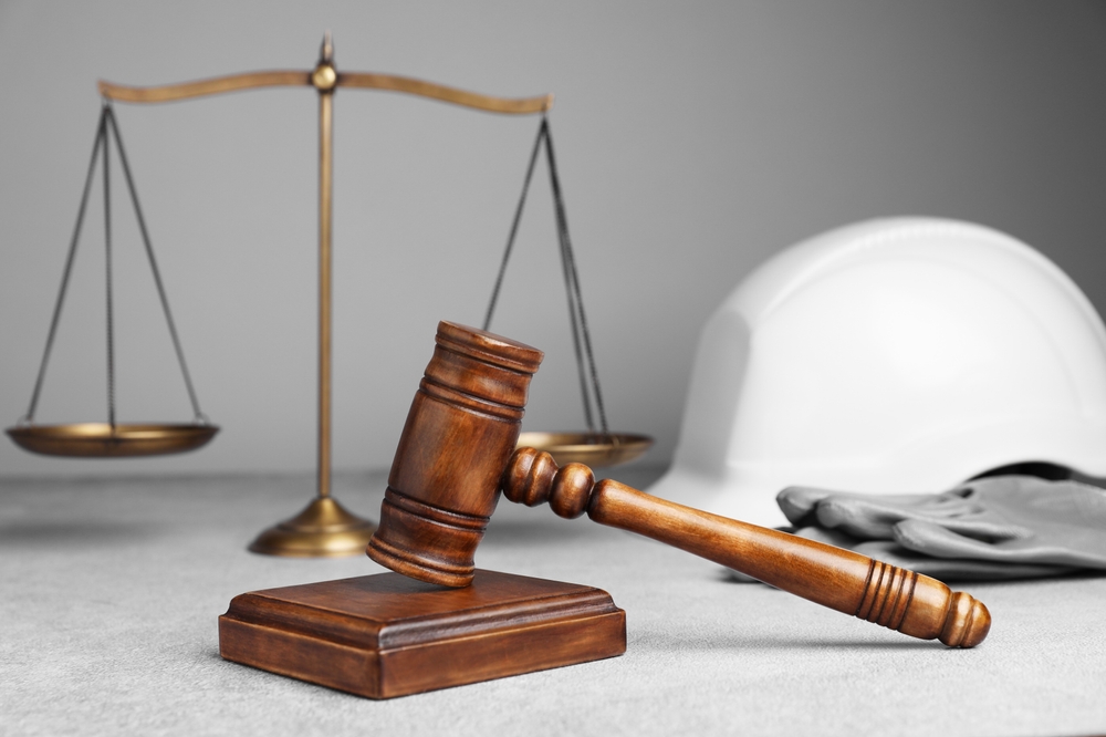 Scales of justice and gavel next to a hard hat illustrating liability in a construction accident lawsuit