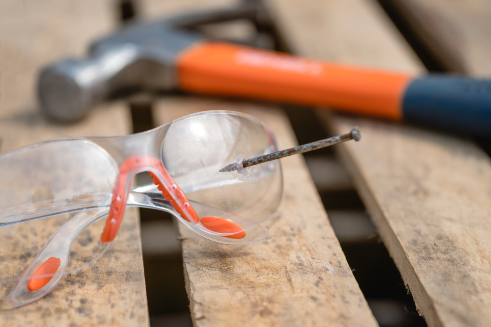 Damaged safety glasses pierced by a nail, demonstrating how defective or inadequate eye protection can lead to serious injuries.