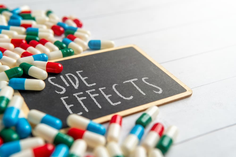 Close-up of a small chalkboard with the words "Side Effects" surrounded by colorful pills. Drug risks, medical warnings, adverse reactions concepts