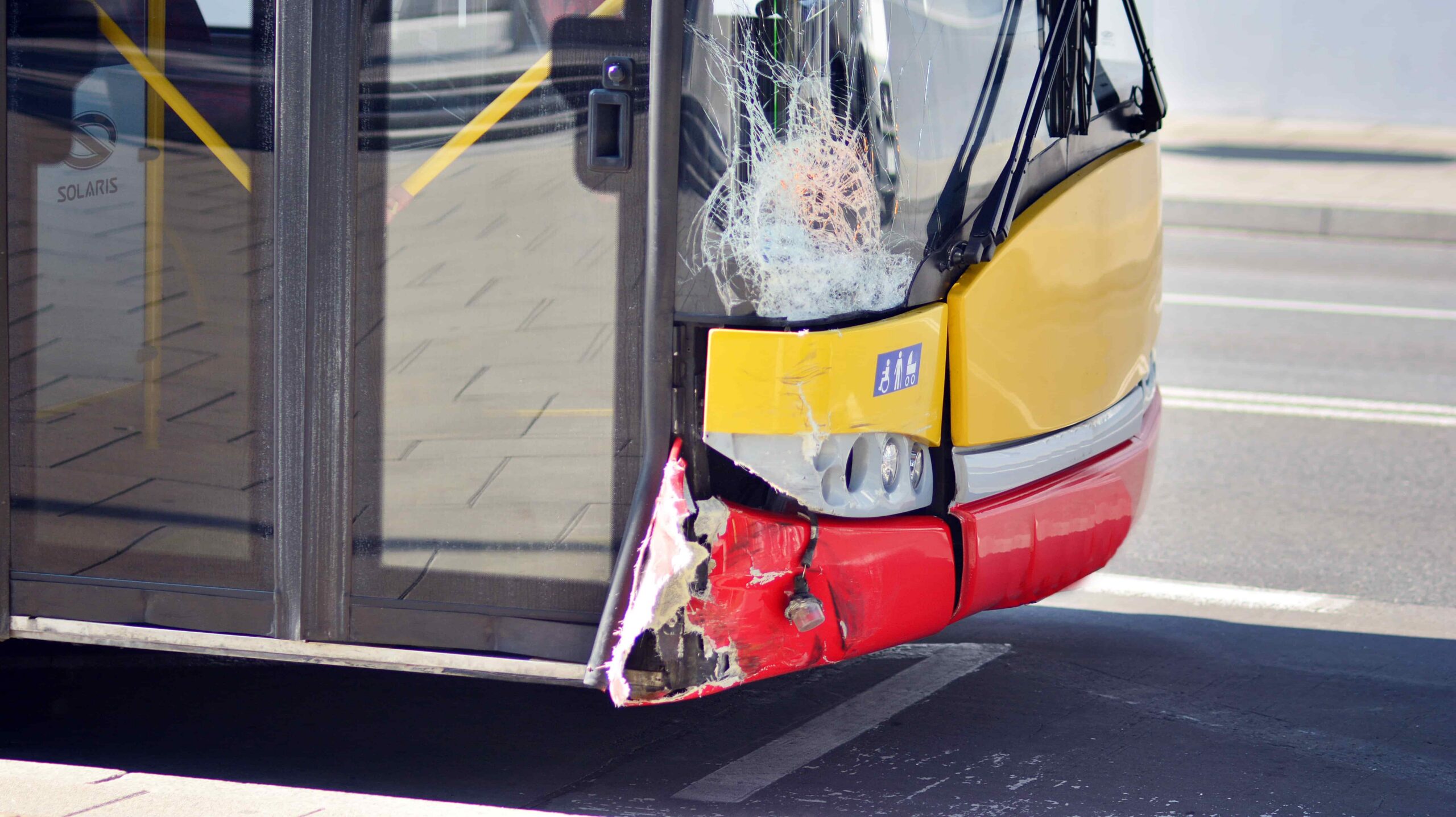 Damaged city bus with cracked windshield and front-end impact, public transportation accident and injury claim concept
