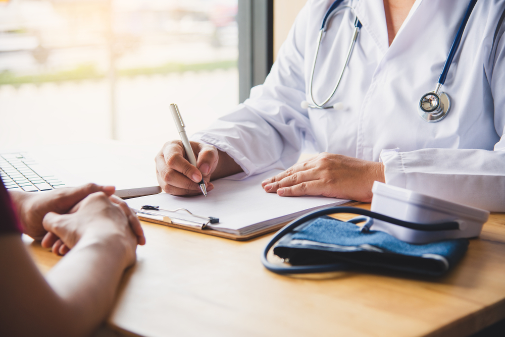 doctor reviews medical background with patient while filling forms