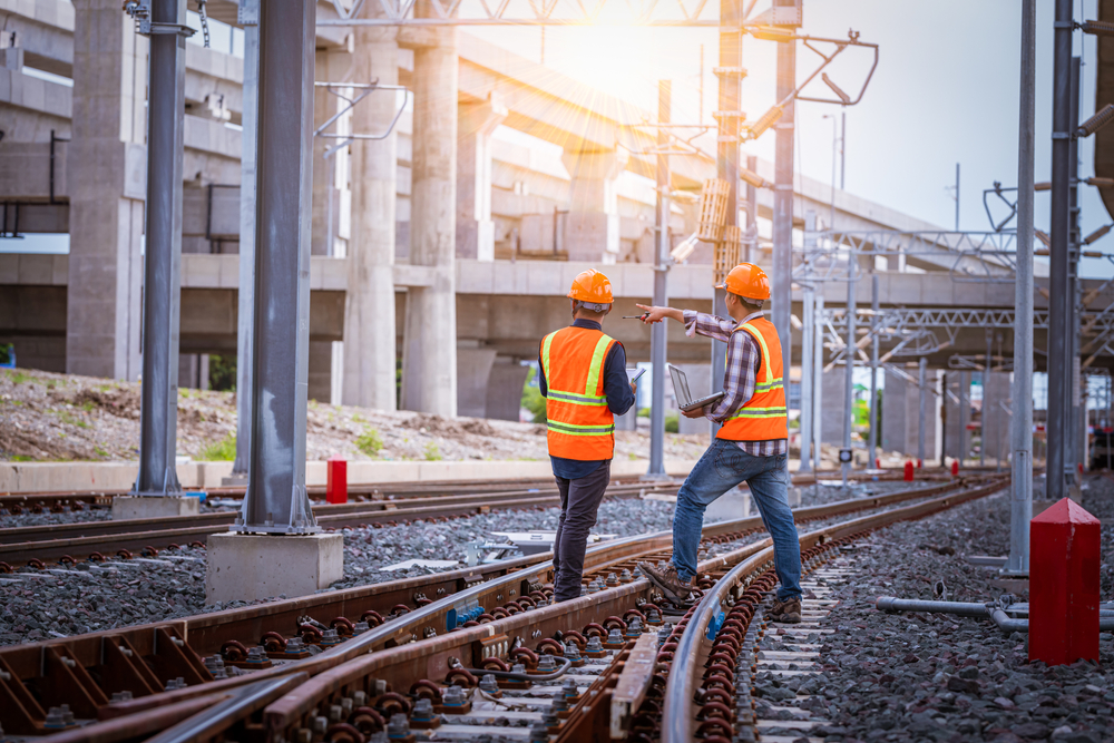 Engineer and construction worker surveying a rail yard