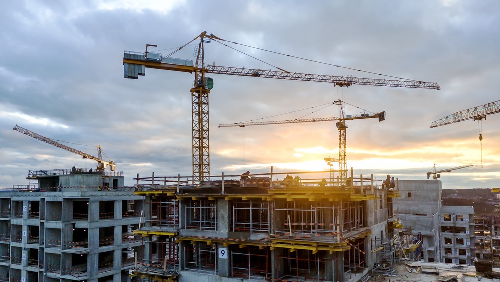 A construction site with large cranes, pictured at sunset
