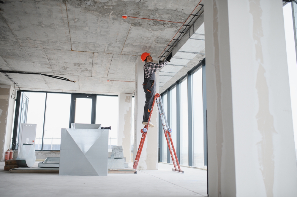 A construction worker on a high-rise jobsite works on a ladder
