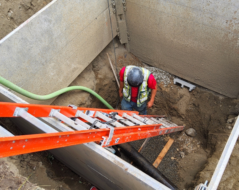A construction worker at the foot of a ladder within a concrete form