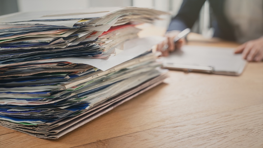 Lawyer at desk with stack of physical paper documentation