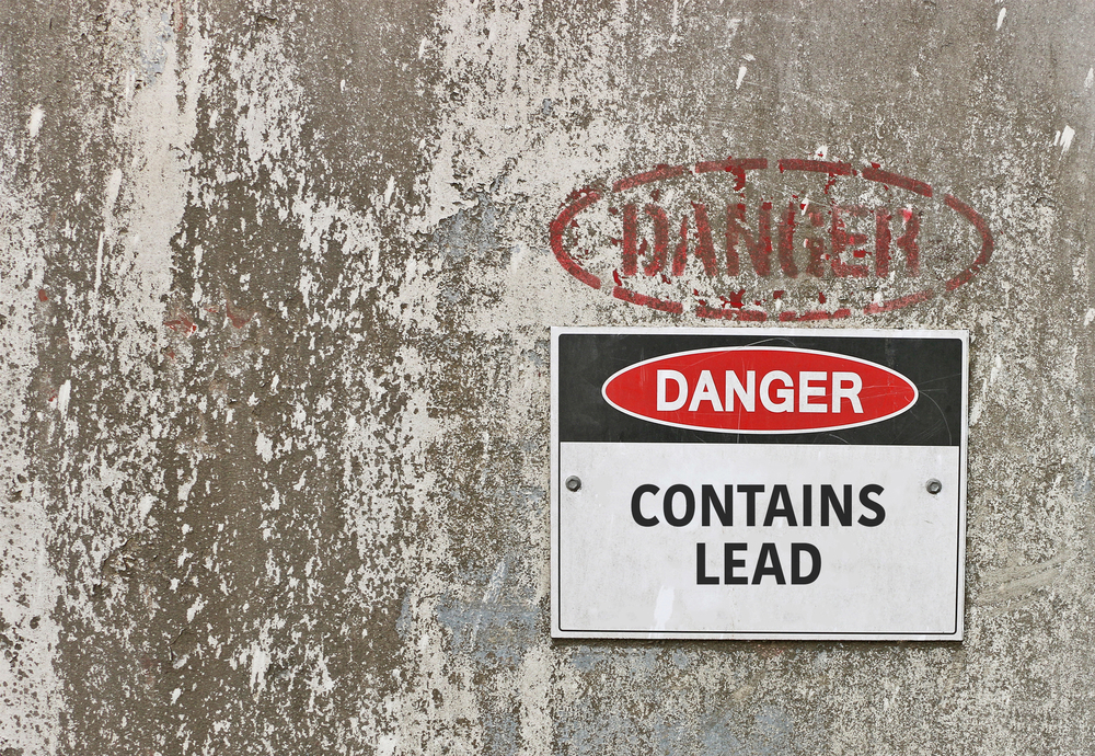 "Danger: Contains Lead" sign on concrete wall